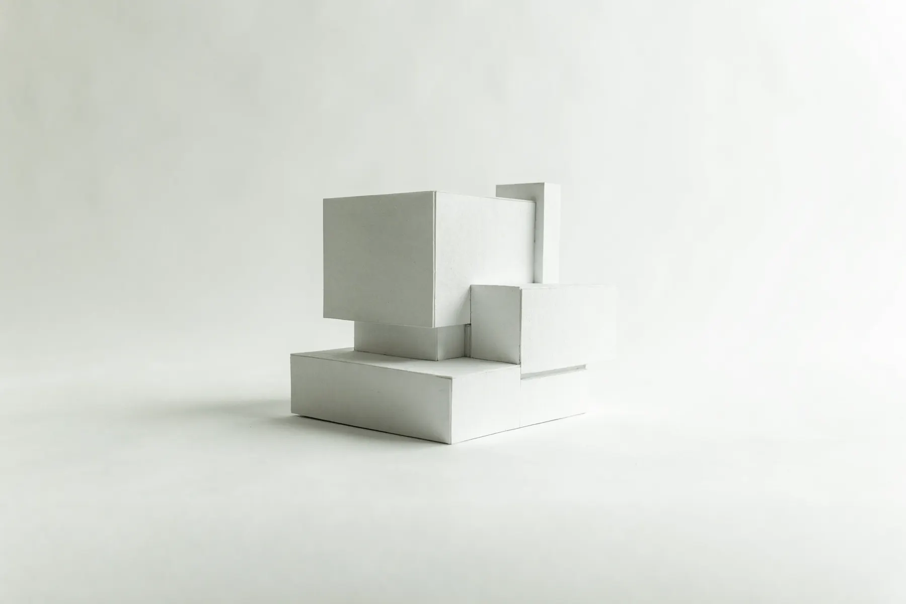 A matte-white architectural massing model on a pale studio surface, a single cobalt reference line running through it at the datum height.