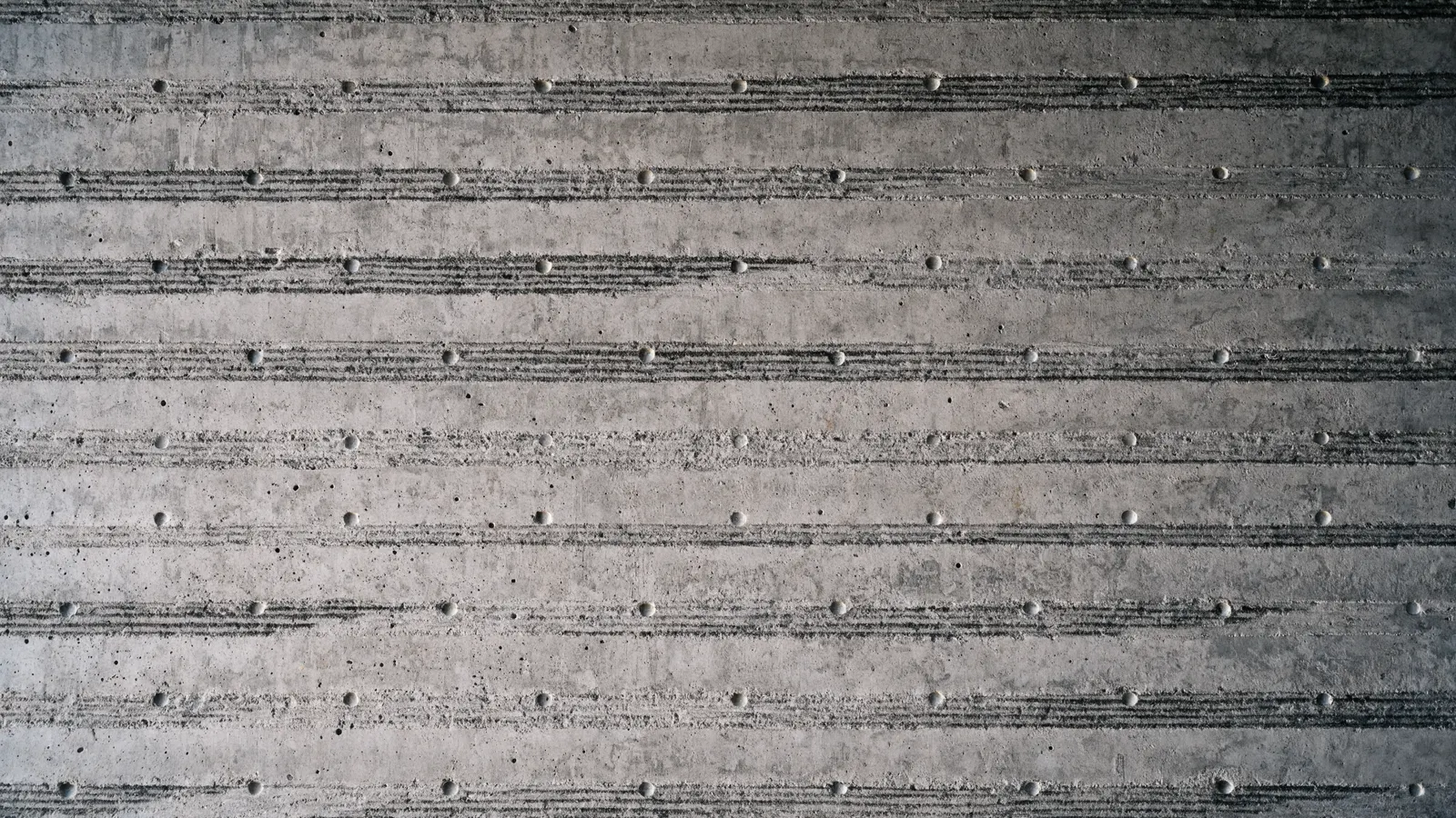 A field of board-formed concrete, the timber grain reading across the frame like a score.